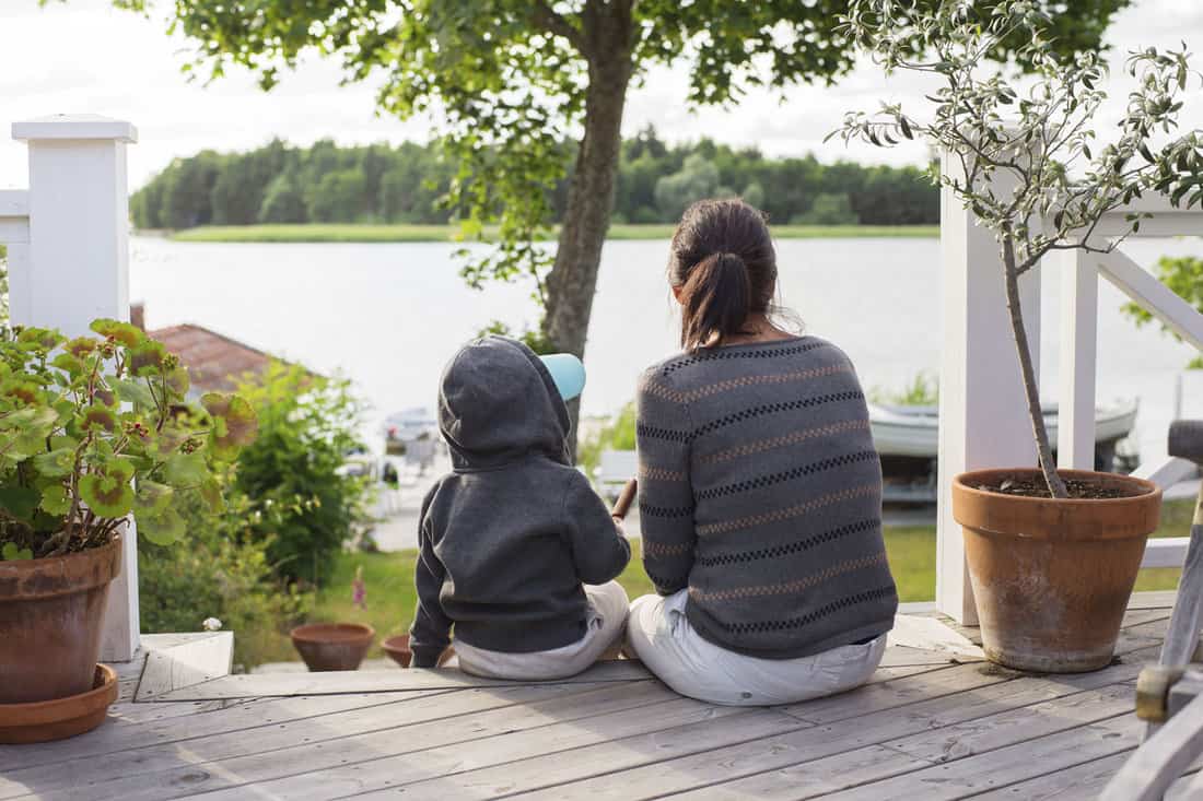 Mother with son sitting on porch and looking at water 