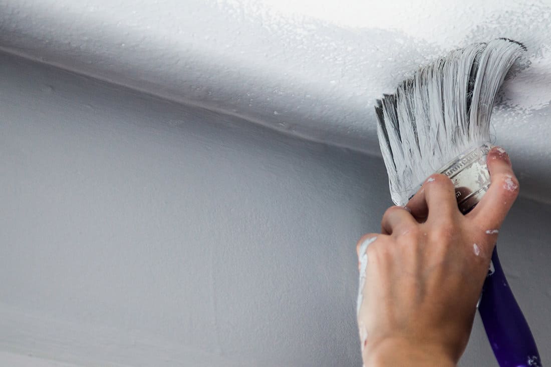 Painting the edges of the ceiling with paintbrush