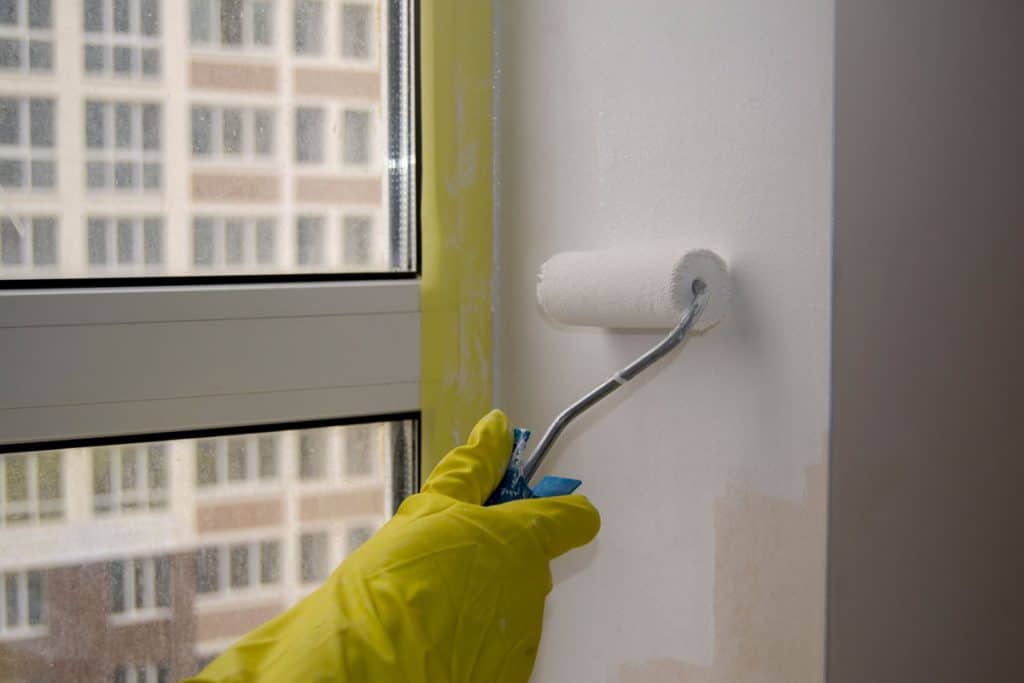 Painting the wall using a roller paint with white paint