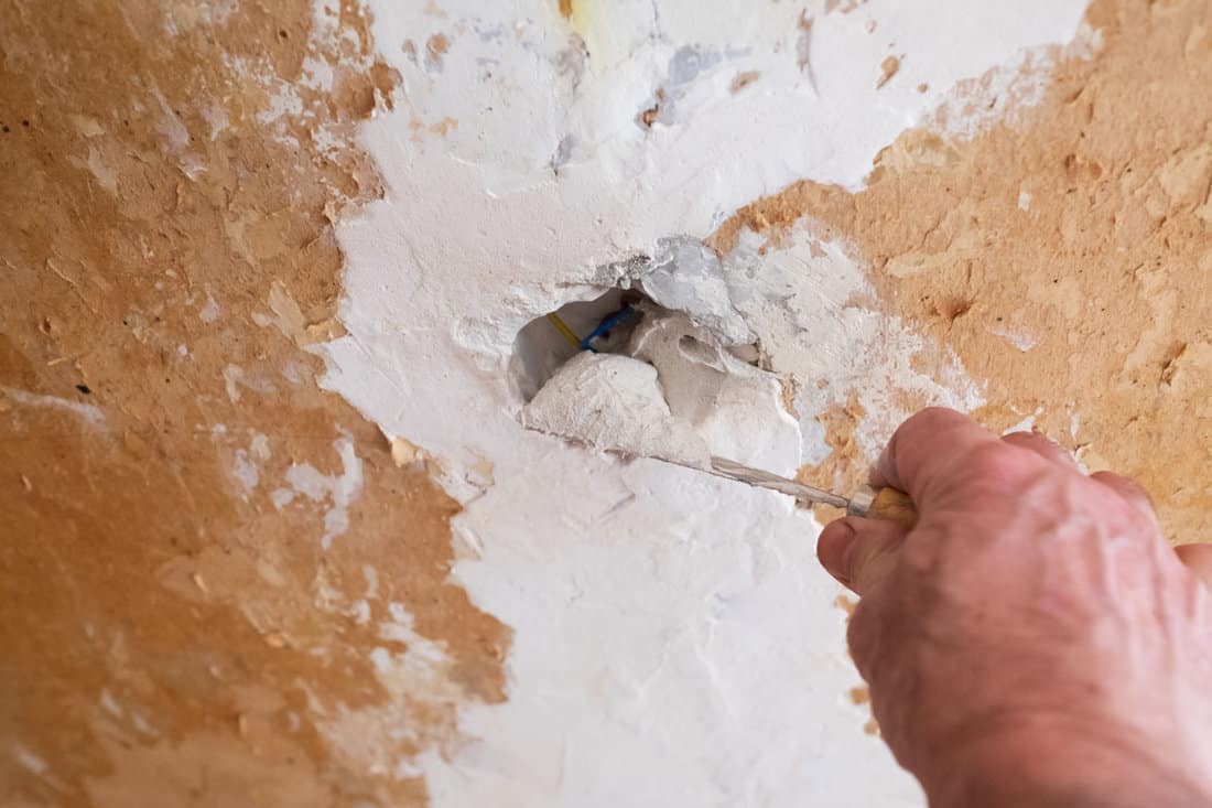 Repairing the wall - Man putting spackle on a hole in the wall