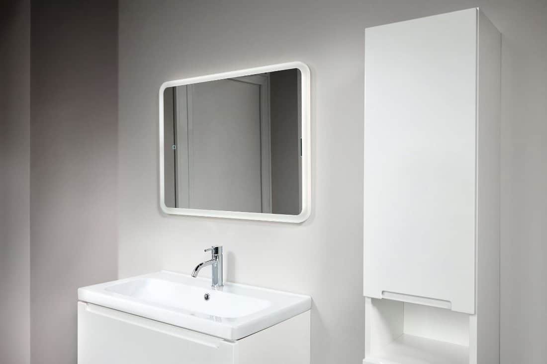 Stoneware countertop bathroom with tired beton wall . White industrial flat loft bathroom with modern countertop basin, square mirror and PVC cupboard.