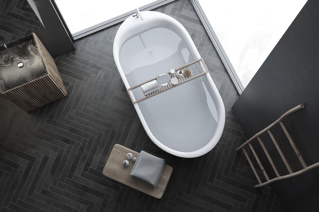 Top view of modern gray wall bathroom interior with black wooden floor, loft windows, ladder, sink and bathtub. 