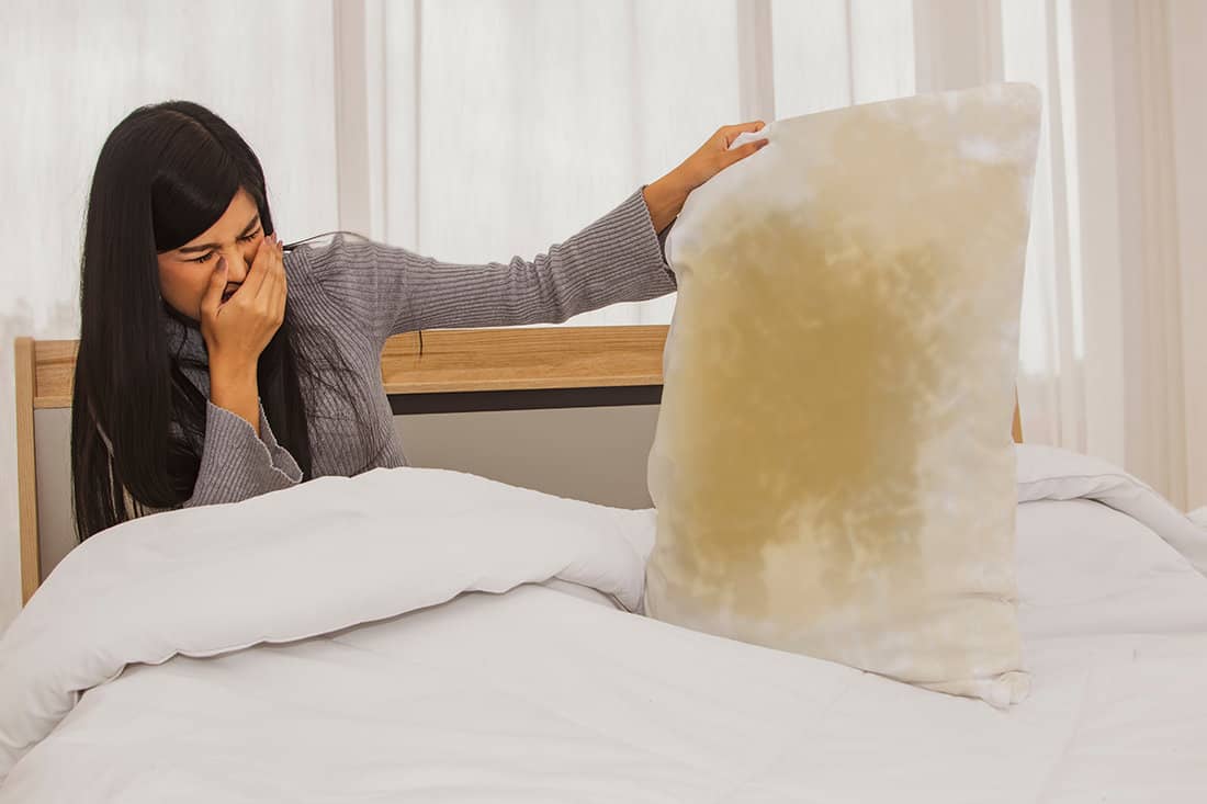 Woman cover nose due to pillow foul smell