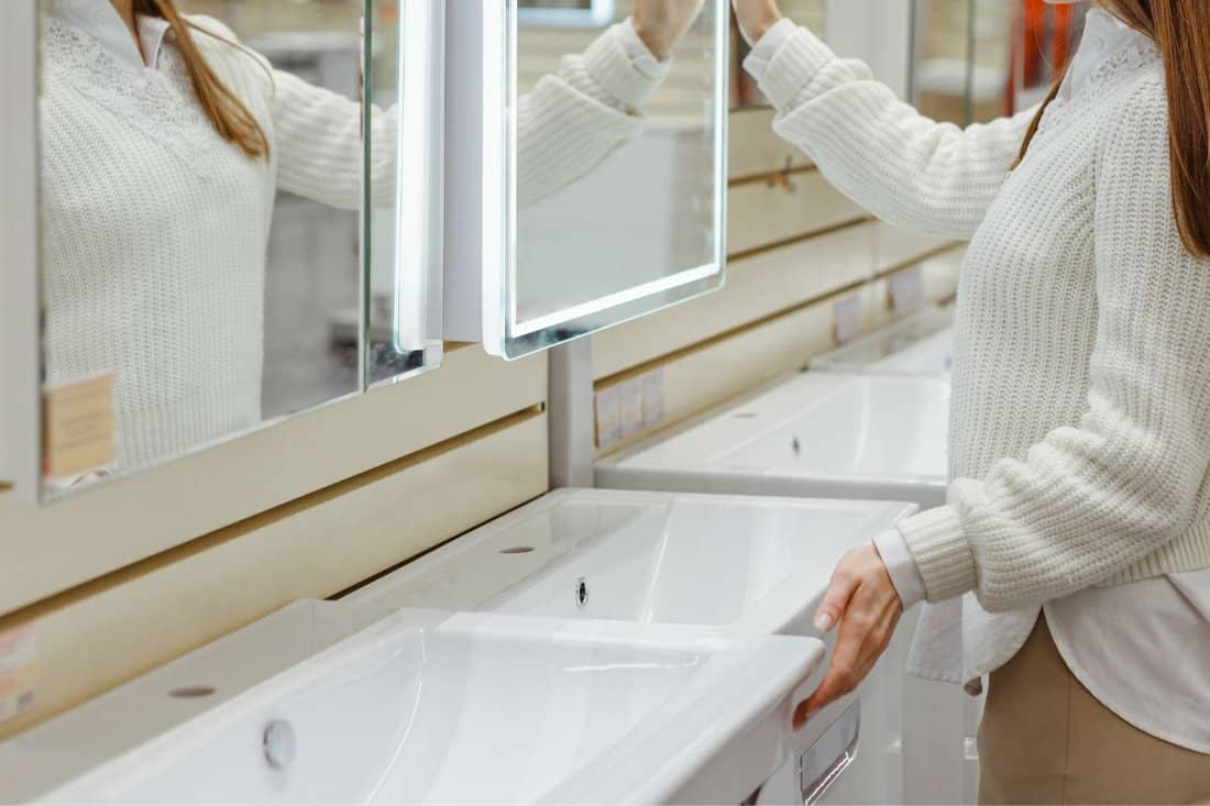 Woman is touching light button on bathroom mirror in shop, hardware store shopping, furniture