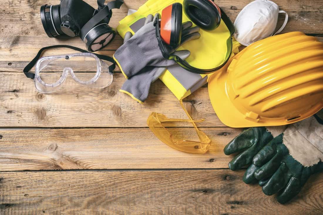 Work safety. Construction site protective equipment on wooden background, flat lay, copy space, top view.