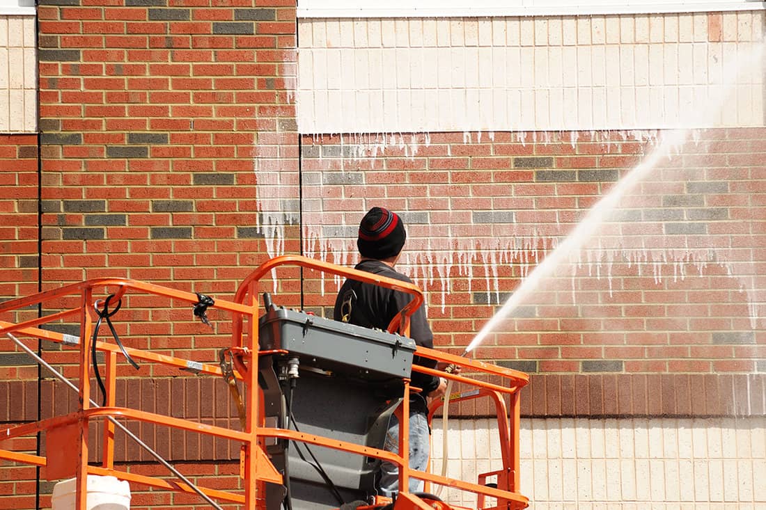 Worker cleaning the exterior wall of building through pressure water