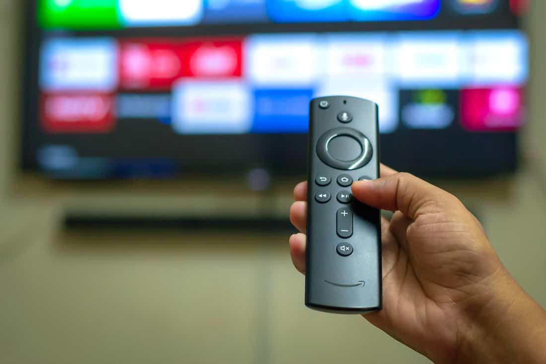 amazon firestick tv remote in hand with tv background