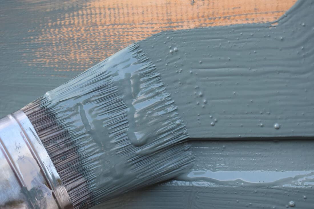 close up paint brush grey color paint applied on the wooden table