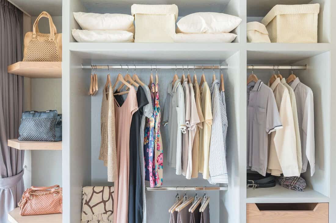 clothes hanging on rail in wooden closet at home