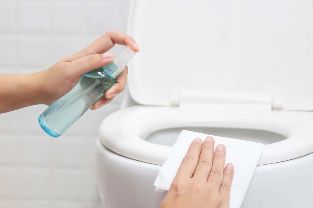 disinfect, sanitize, hygiene care. people using alcohol spray on toilet seat lid and frequently touched area for cleaning and disinfecting