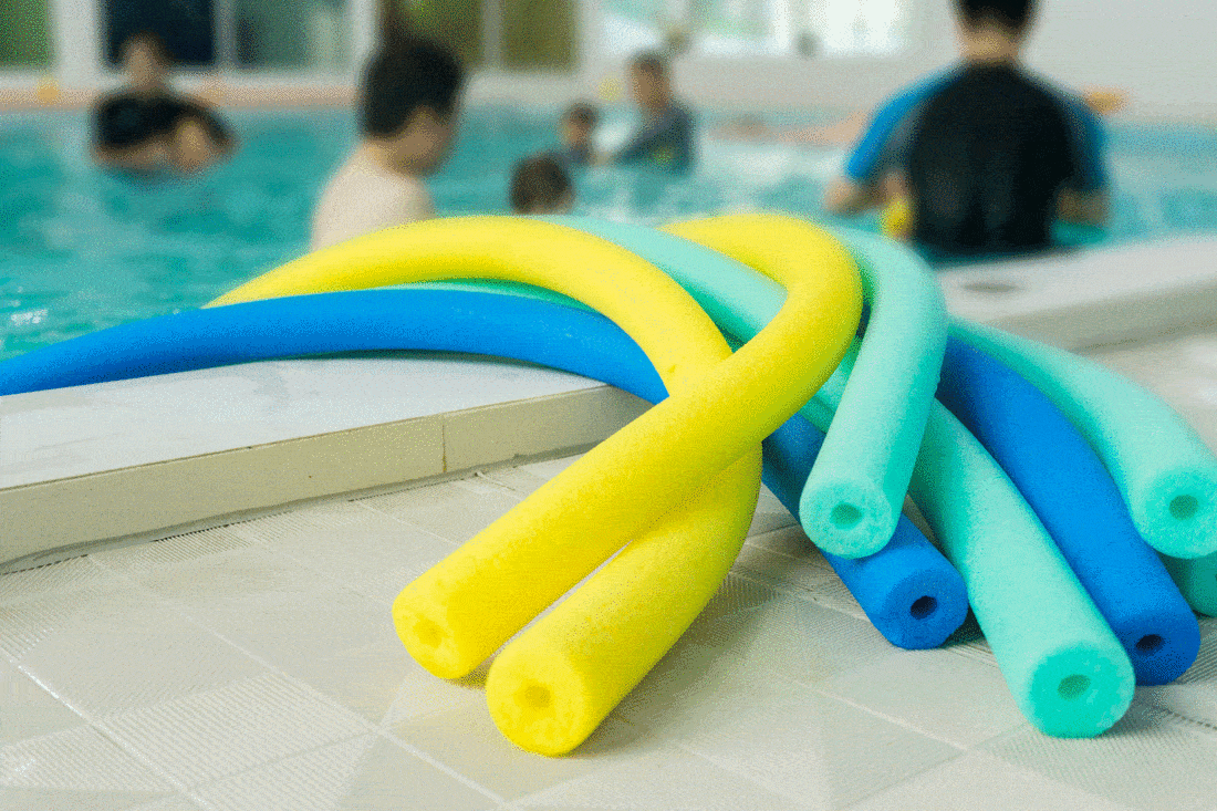 group of floating swim noodles in different colors for mother and farther teaching kid in swimming pool.selective focus 