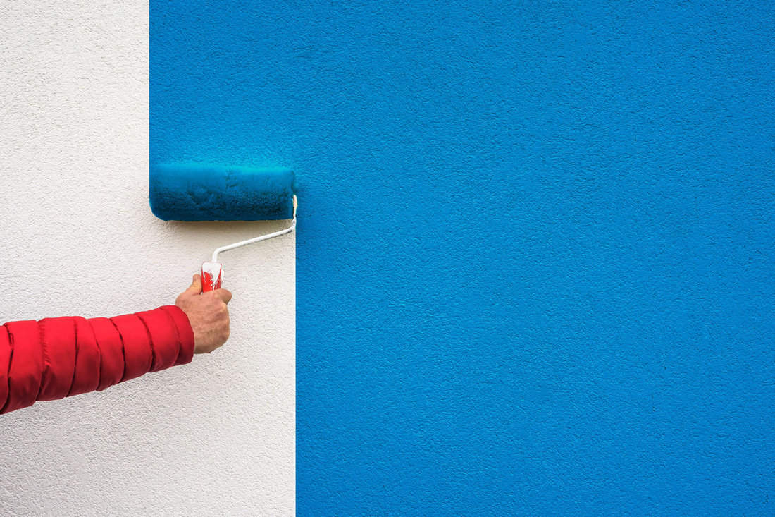hand holds paint roller and painting a wall 