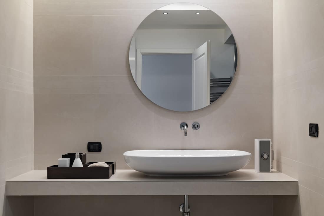 internal shots of a modern bathroom in foreground of counter top washbasin whose walls are coated of p