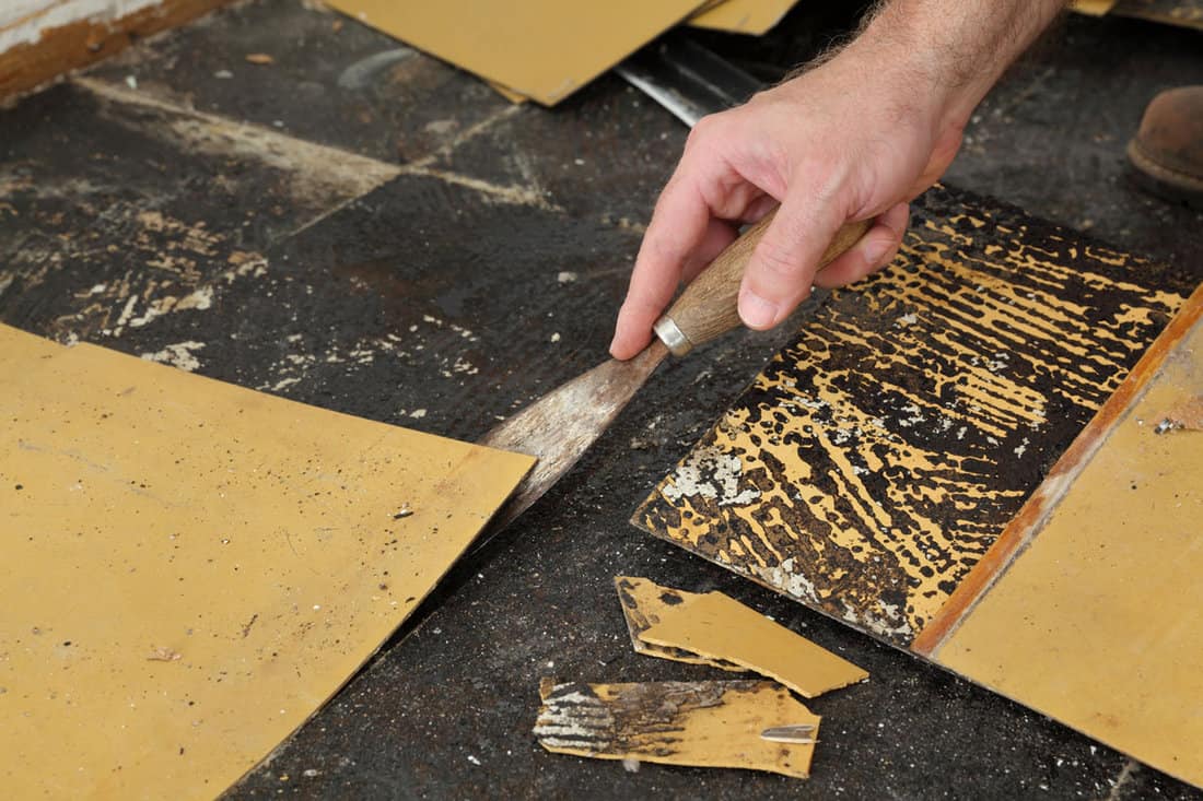 worker removing old vinyl tiles kitchen