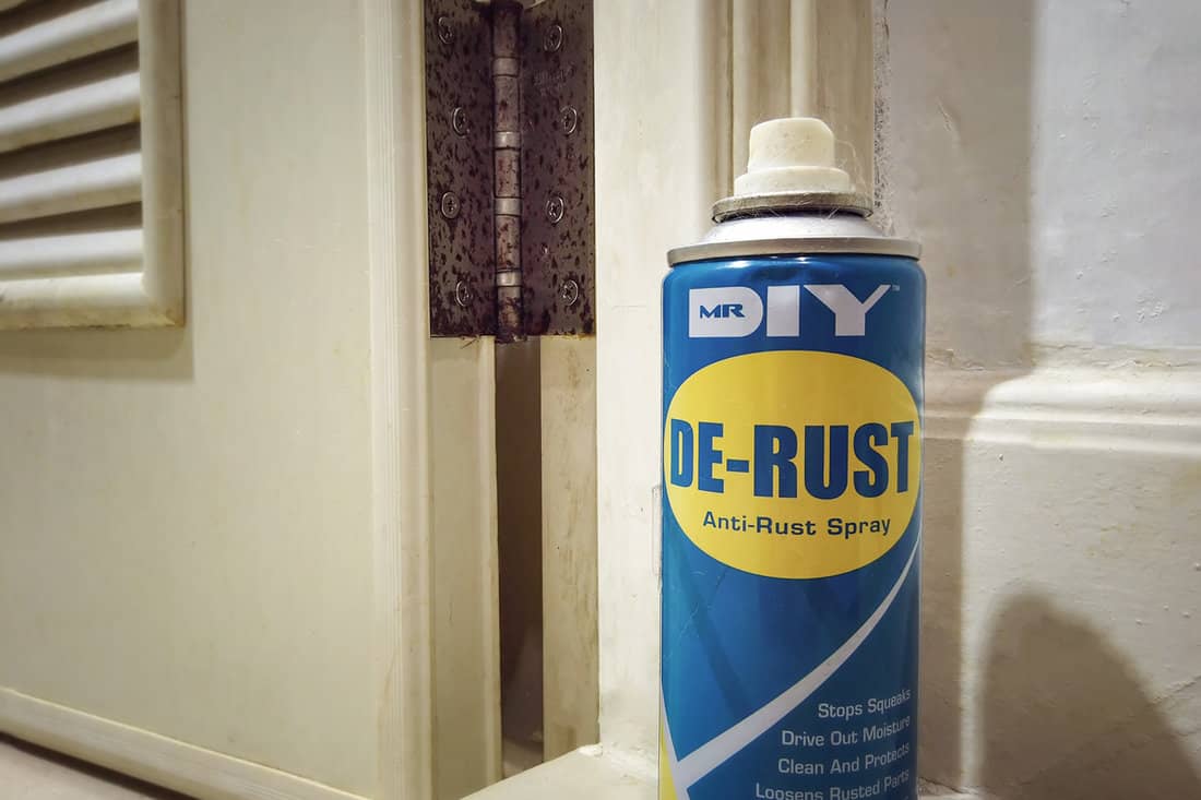 Can of Mr. DIY De-Rust Lubricant Spray next to a Rusty Door Hinge