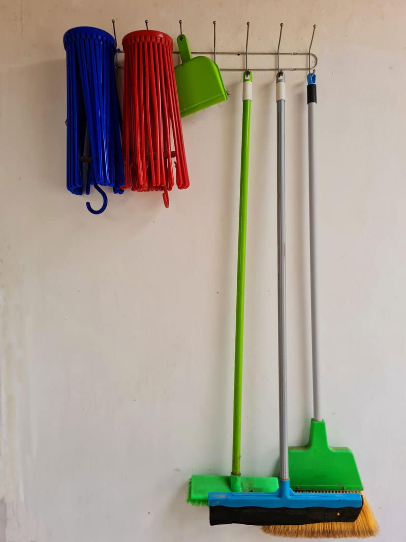 Cleaning tools hanging on the wall. Floor squeegee, broom and brush. 
