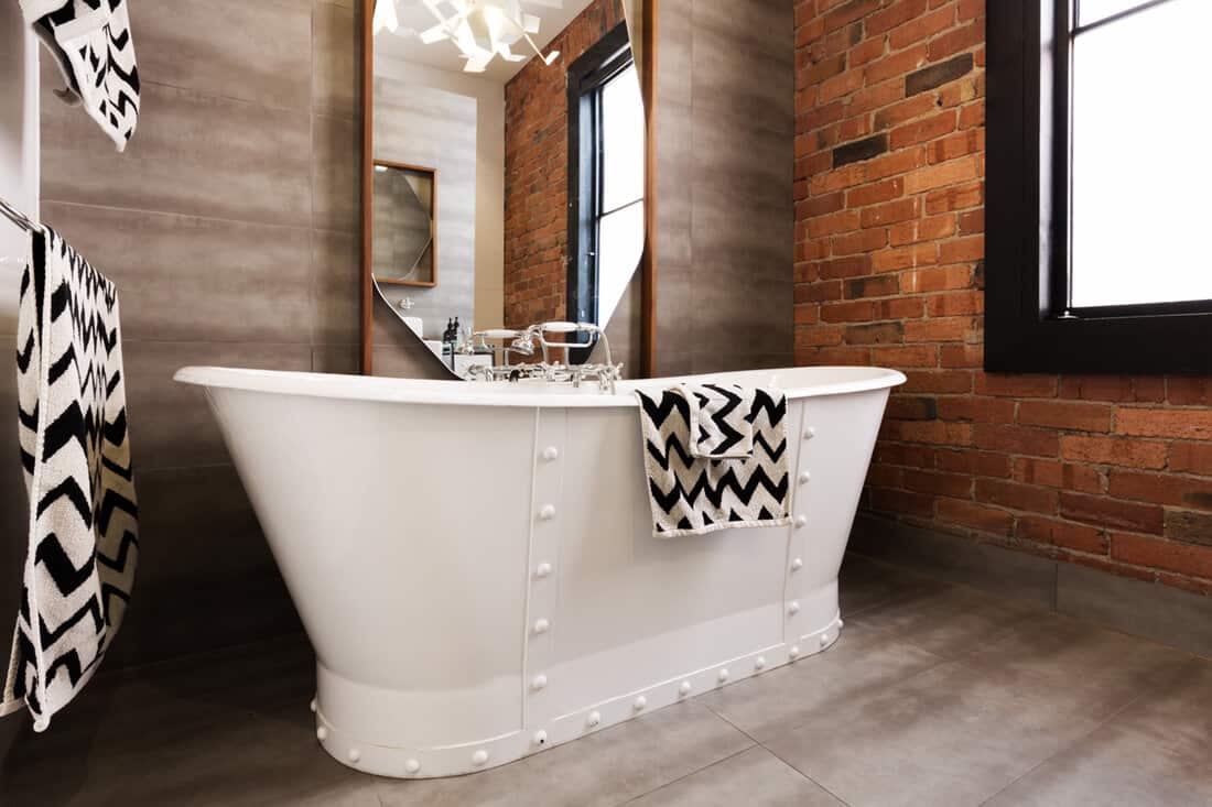 Close up of white freestanding bat tub in vintage interior styled bathroom