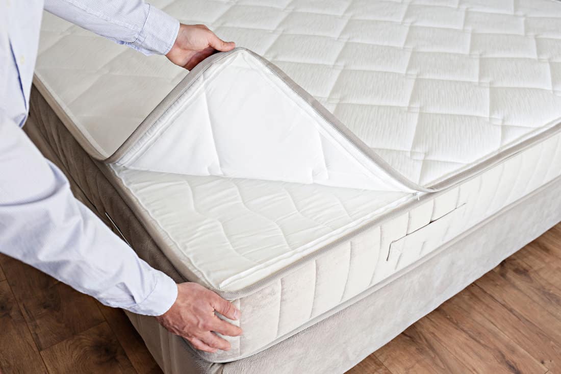 Cropped shot of man showcasing the waterproof topper for white orthopedic mattress