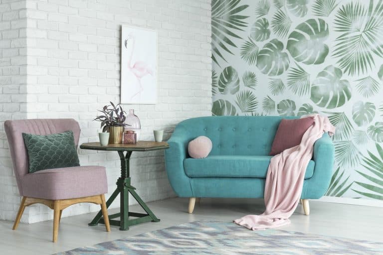 Green table with a plant between pink chair and blue sofa in floral living room with wallpaper and poster, How To Remove Wallpaper From Mobile Home Walls