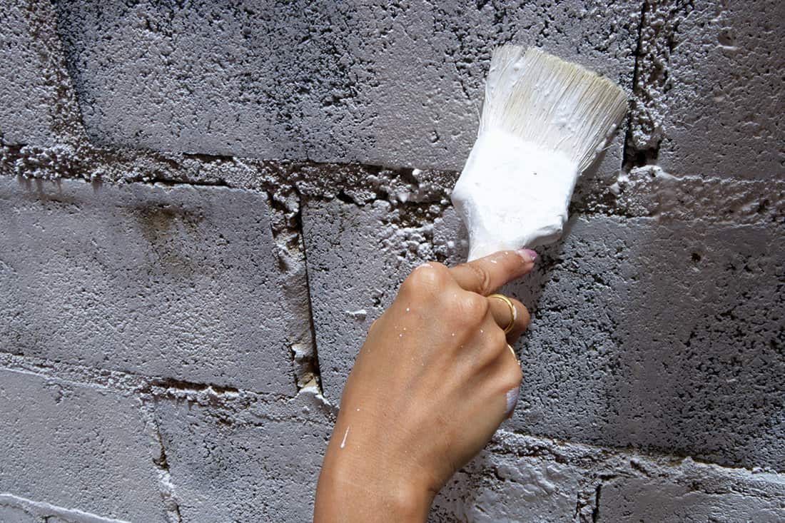 Handyman painting concrete block wall