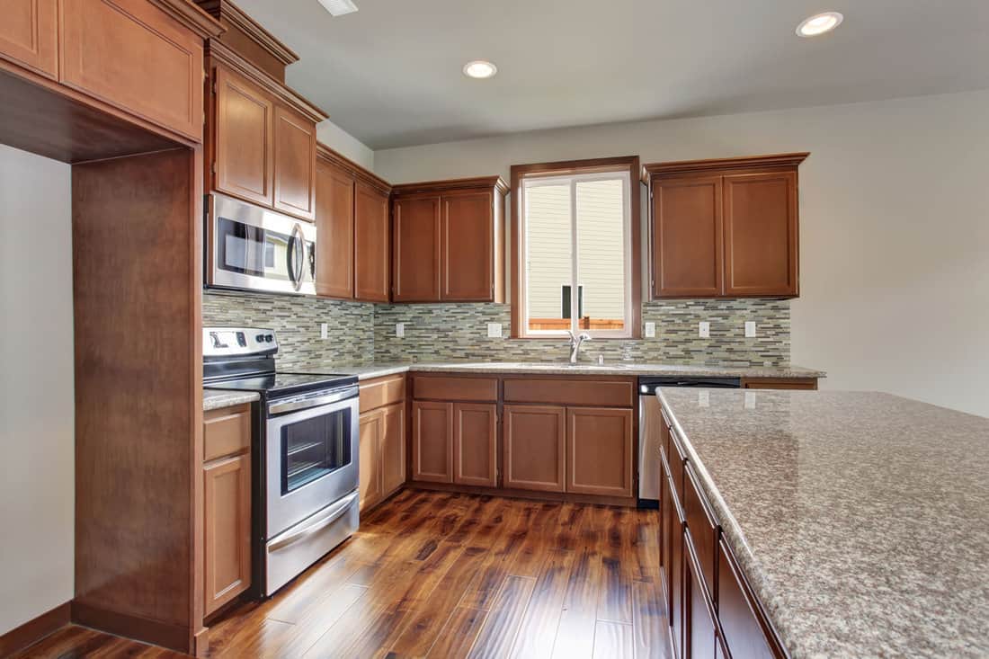 New 2015 American middle class kitchen. Cherry wood color of cabinets and laminate flooring. 