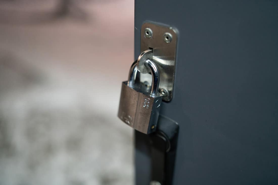 Padlock on gate of small gray container closeup