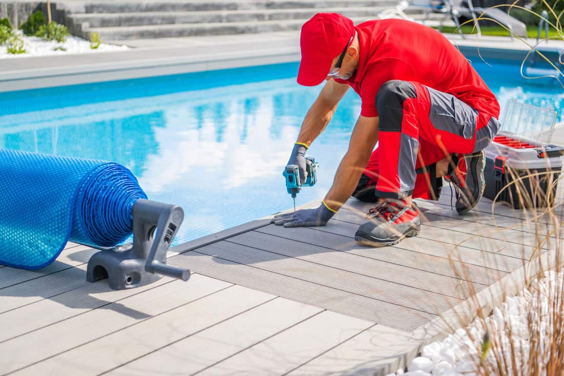 Professional Swimming Pools Worker Finishing Composite Outdoor Pool Deck Installation