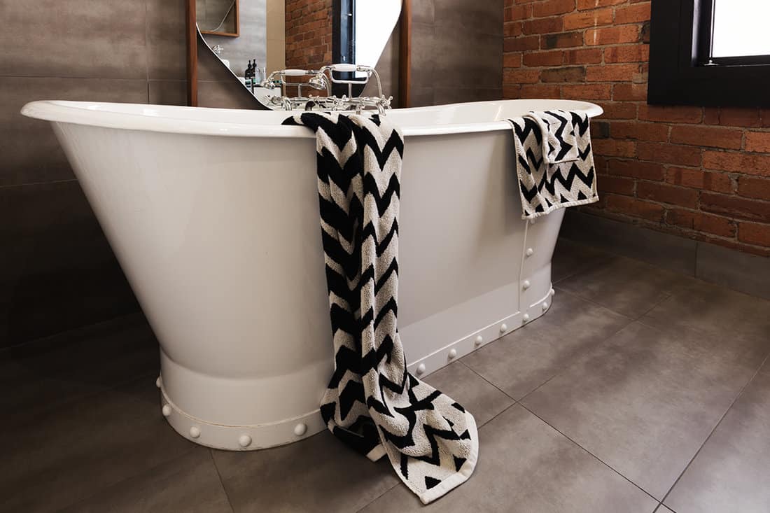 Styled bath towel draped over a freestanding vintage style bath tub