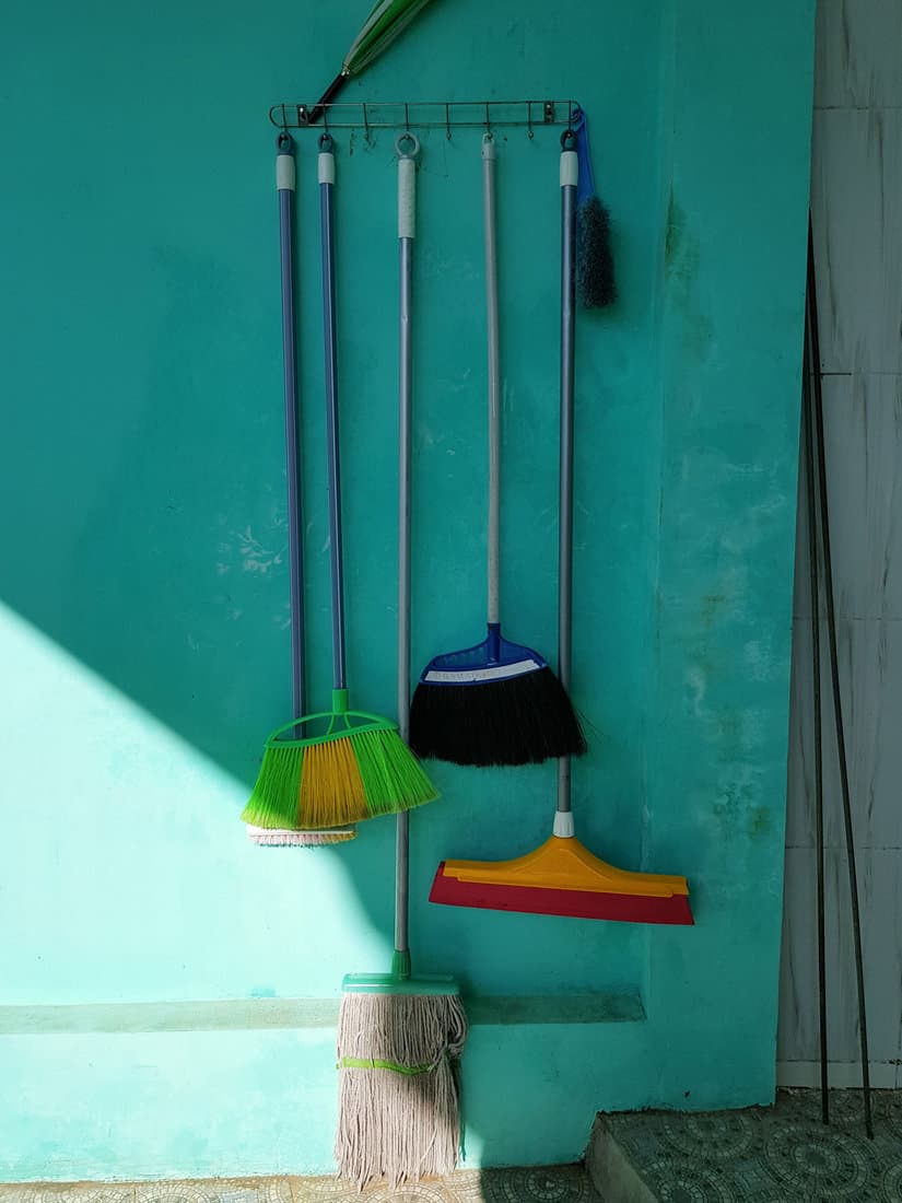 The brooms are hanging on the wall before it is used in the morning.