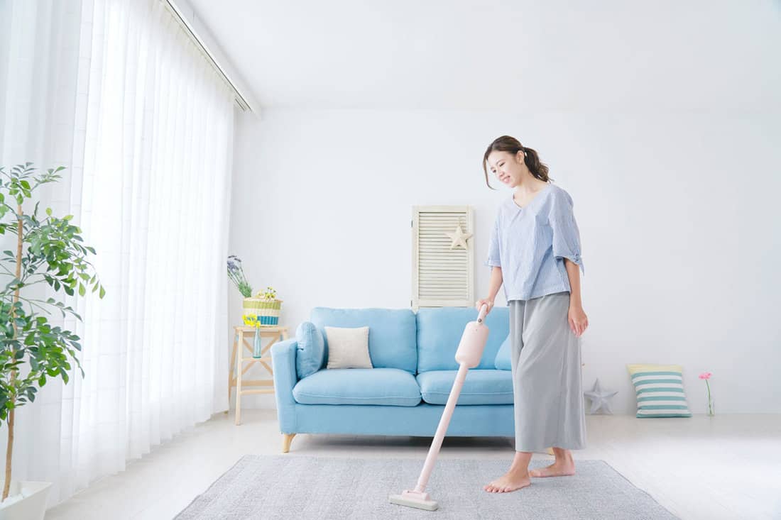 Woman cleaning the living room with a vacuum cleaner