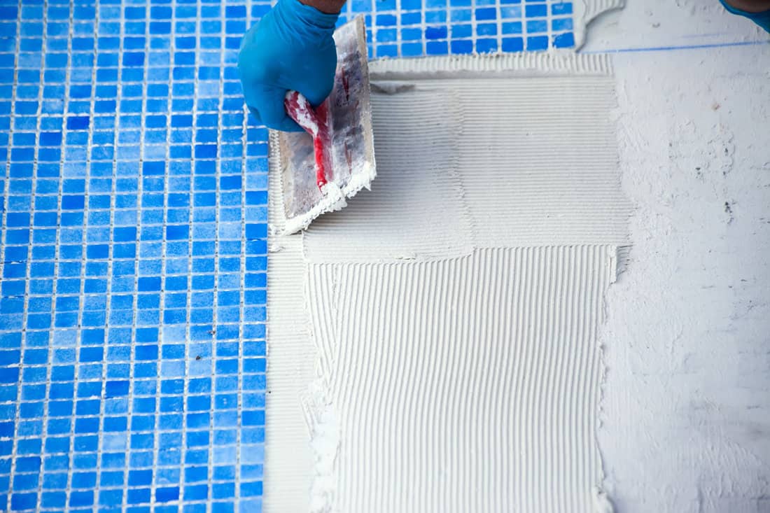 Worker laying tile in the pool