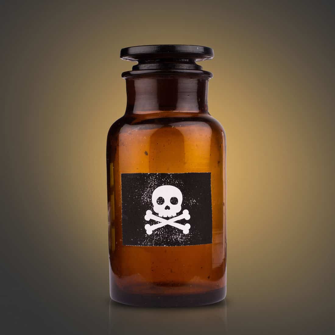 front view of brown medical glassware with glass cap and the poison sign label on dark background 