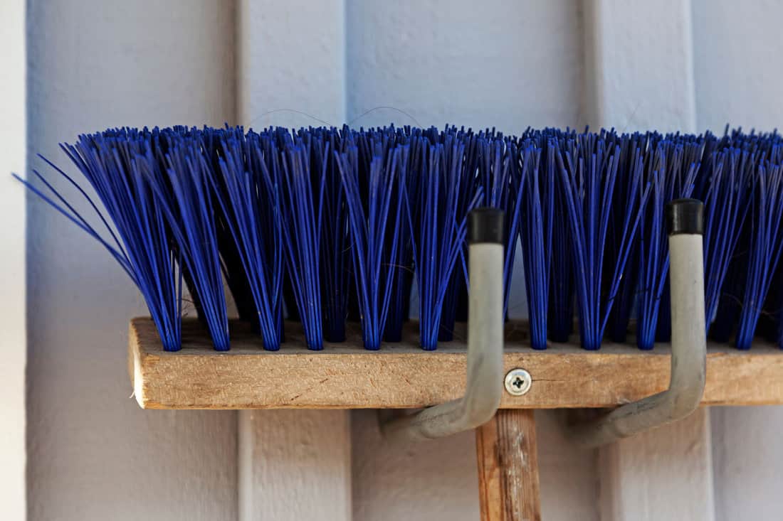 part of a blue broom hanging on a wall 