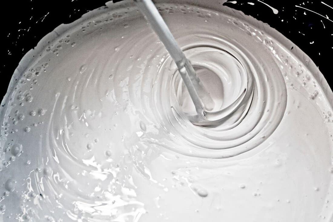 stir white paint in a black bucket.