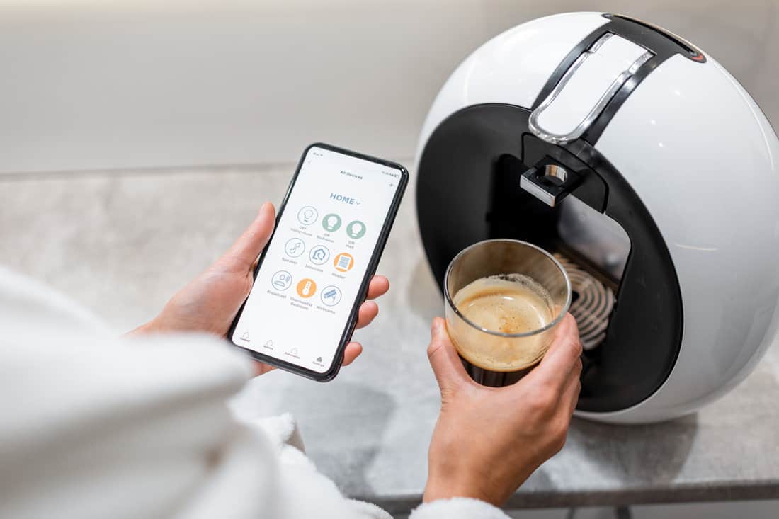 Controlling coffe machine with a smart phone, close-up on phone with launched smart home application