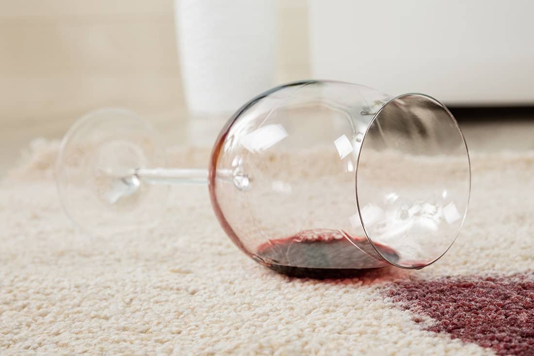 High angle view of red wine spilled from glass on carpet