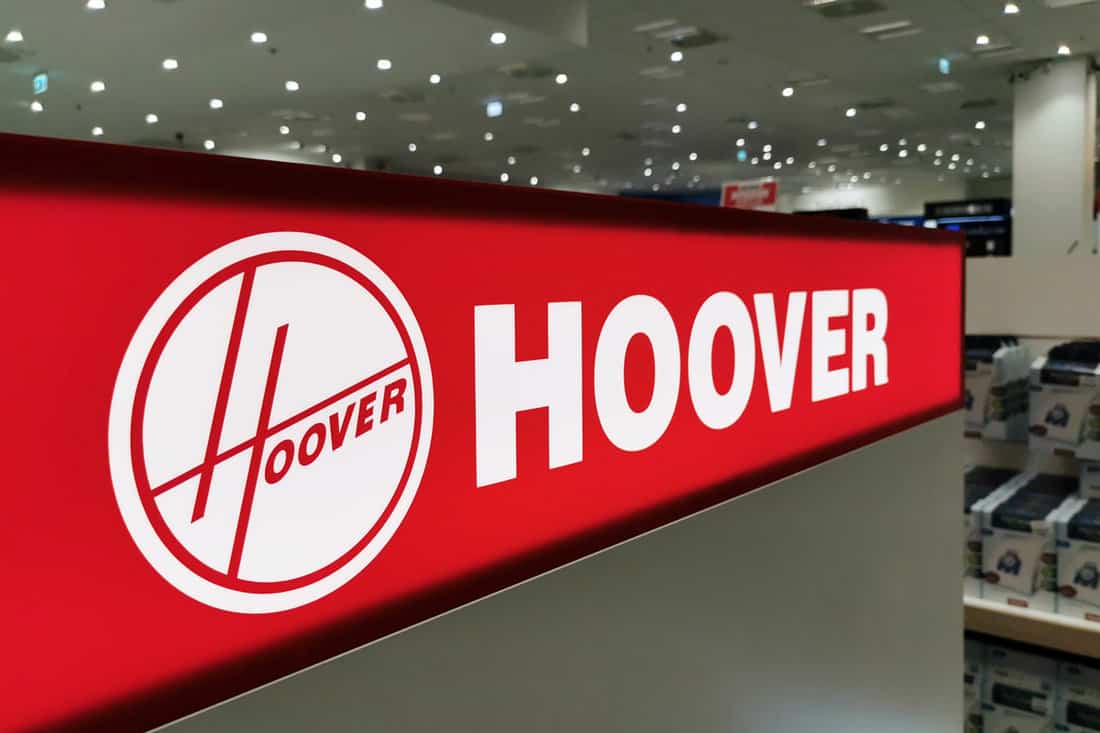 A closeup of a red illuminated Hoover logo in electronics and home appliance store