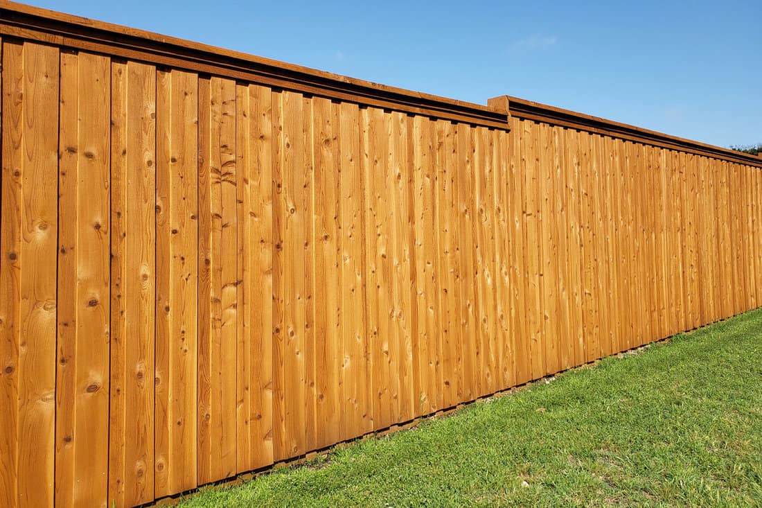 A tall wooden fence with a support on top for strong wind conditions