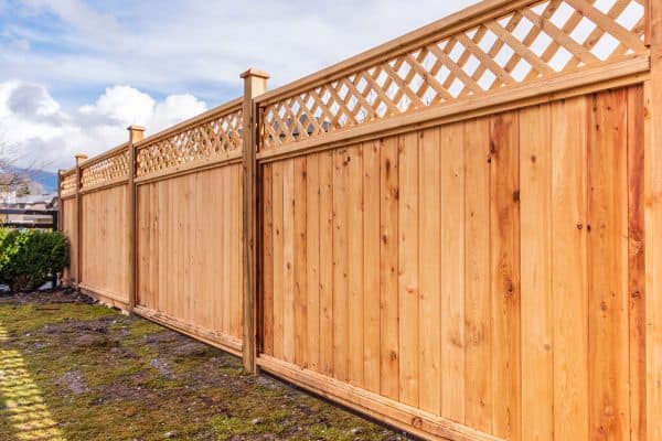 A wooden fence with a lattice pattern on top, Should A Fence Be Level Or Follow The Ground?