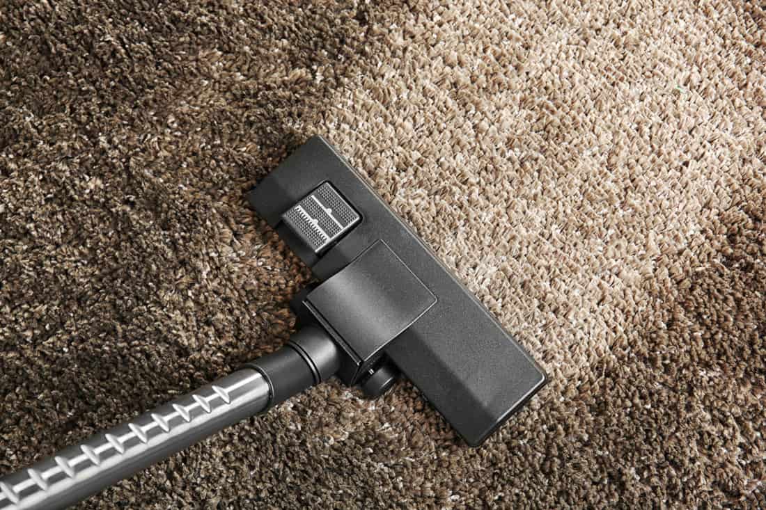 Cleaning concept - vacuum cleaner on grey soft carpet