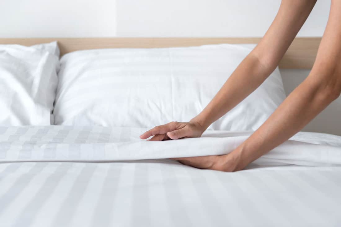 Hand set up white bed sheet in room 