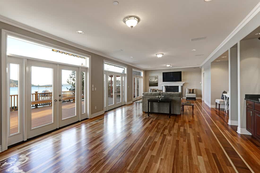 Luxury spacious family room interior with wall of glass doors leading out to spacious deck and facing the lake