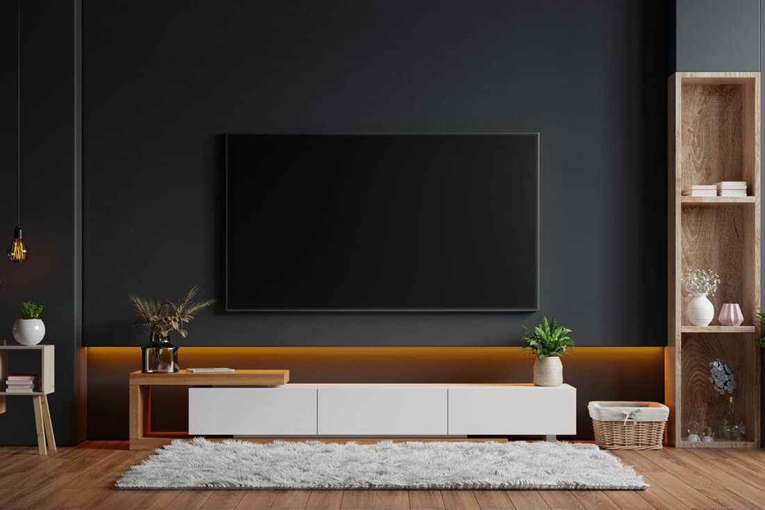 Mockup a TV wall mounted in a dark room with a black wall.3d rendering