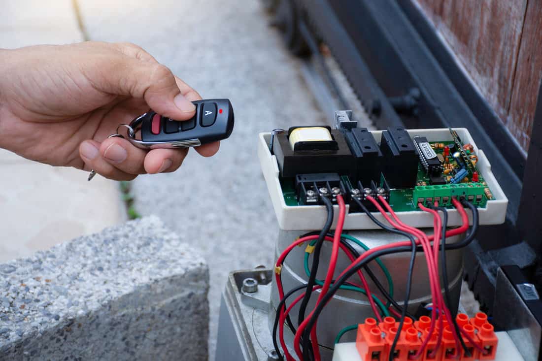 Technician man hand using remote control, testing and checking the functional of motor gear of sliding automatic gate