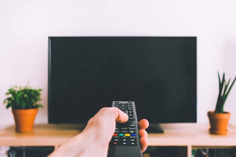 Television with remote control in hand mockup, How Often Should You Replace Your Television