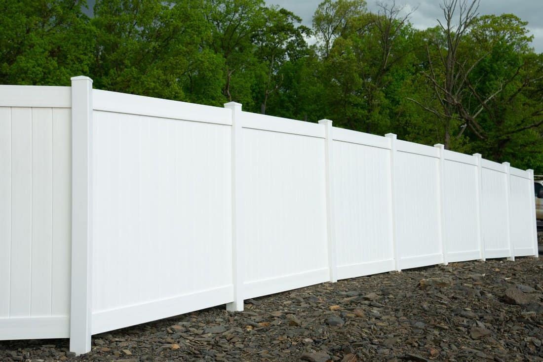White vinyl fence fencing of private property grass plastic.