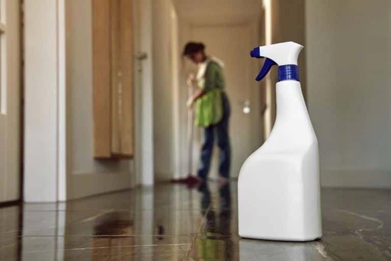 empty disinfectant spray bottle on the floor with young woman during on cleaning. - Does Rubbing Alcohol Damage Hardwood Floors