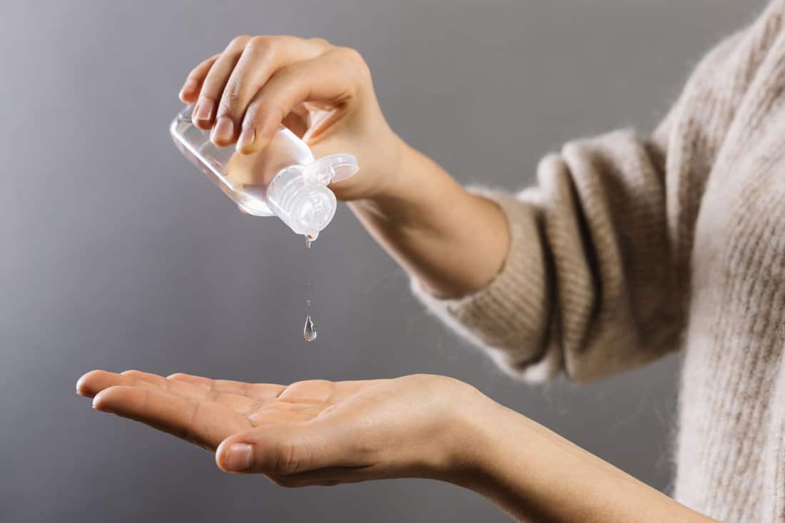 A woman pouring rubbing alcohol on her hand