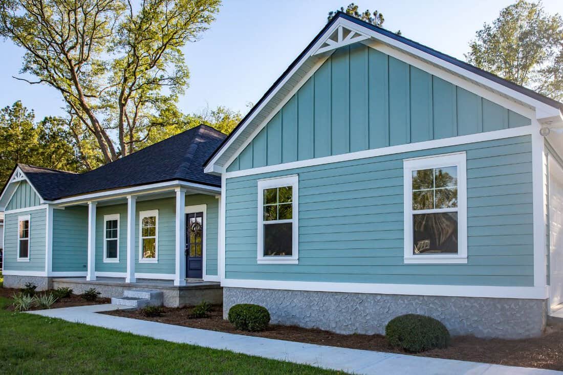 Front view of a brand new construction house with blue vinyl siding, a ranch style home with a yard