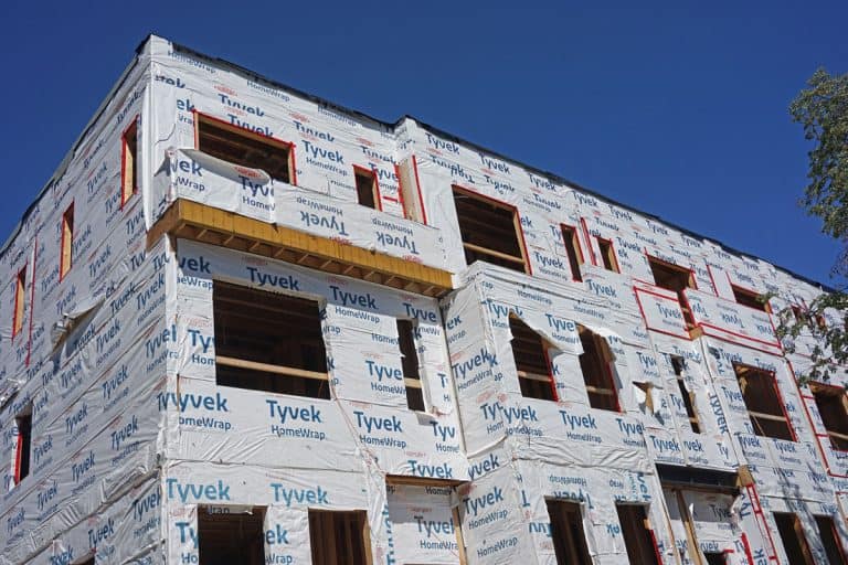 A huge house under construction covered in house wrap, Can House Wrap Get Rained On? Debunking Weather-Related Myths